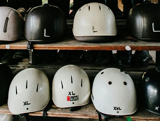 Multiple different bike helmets on a shelf organised by size.